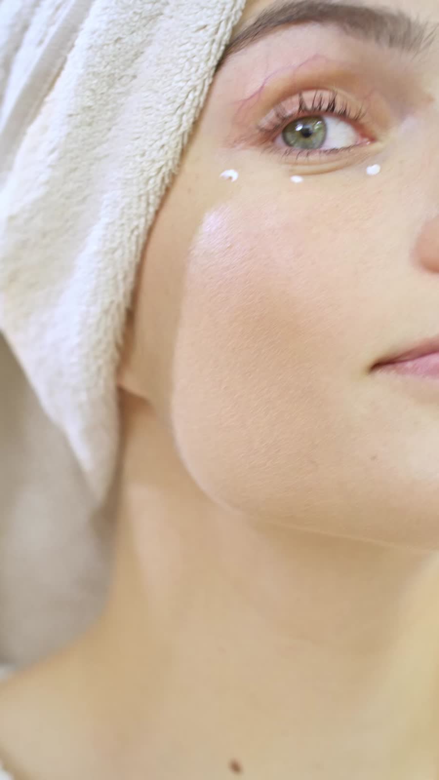 A young woman applying cream under her eye